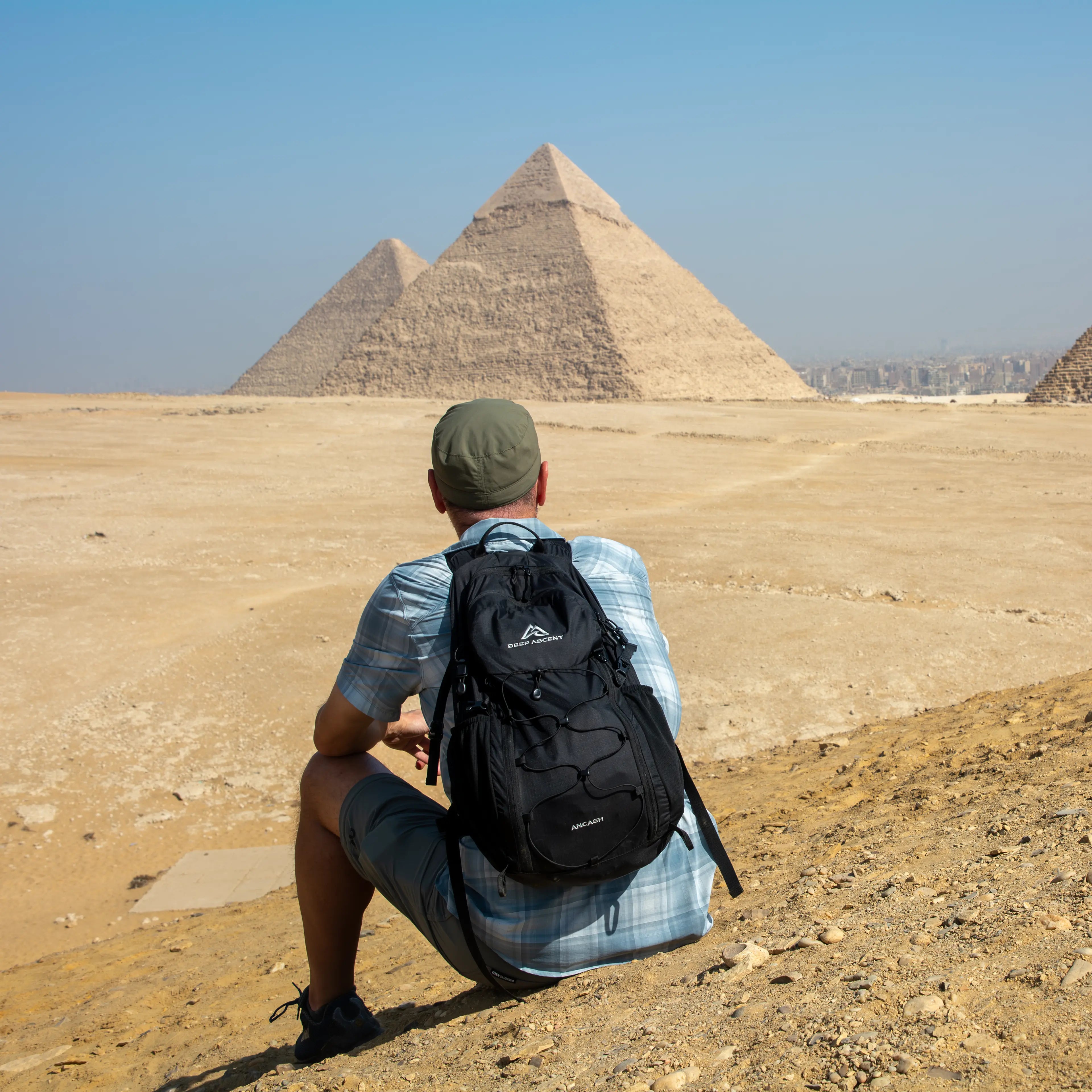 Person wearing the Ancash Packable Daypack sitting in front of the Pyramids of Giza.