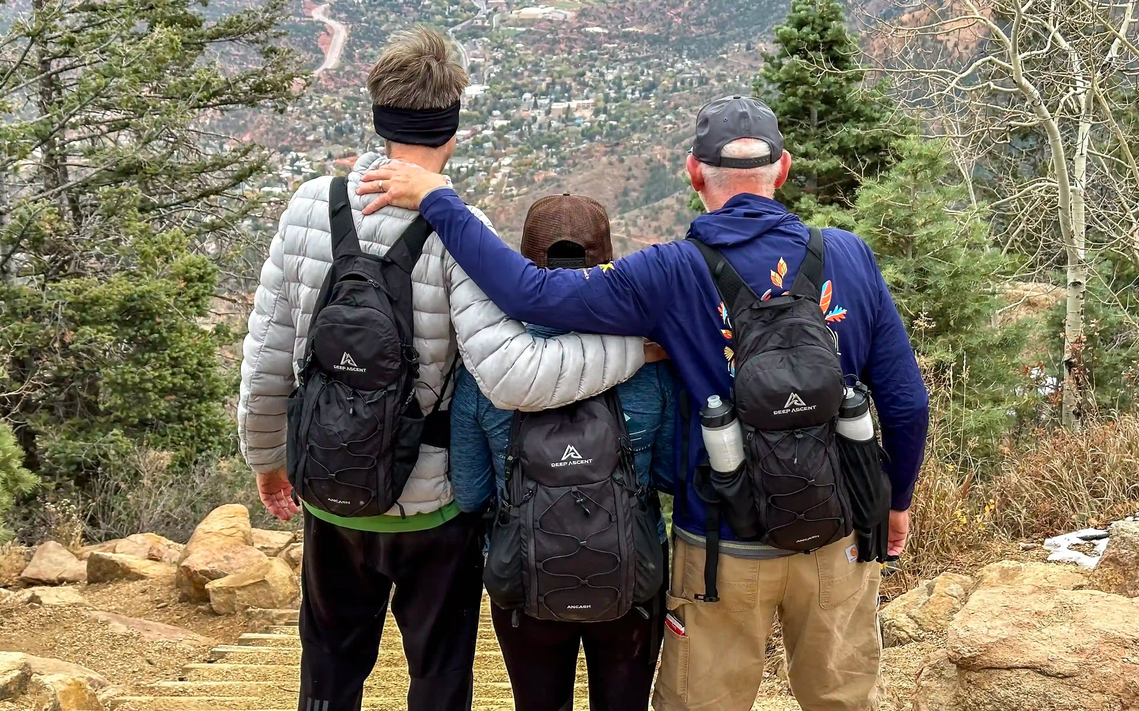Hikers overlooking Colorado Springs from the summit of Manitou Incline in Colorado, each wearing the Ancash Packable Daypack by Deep Ascent.