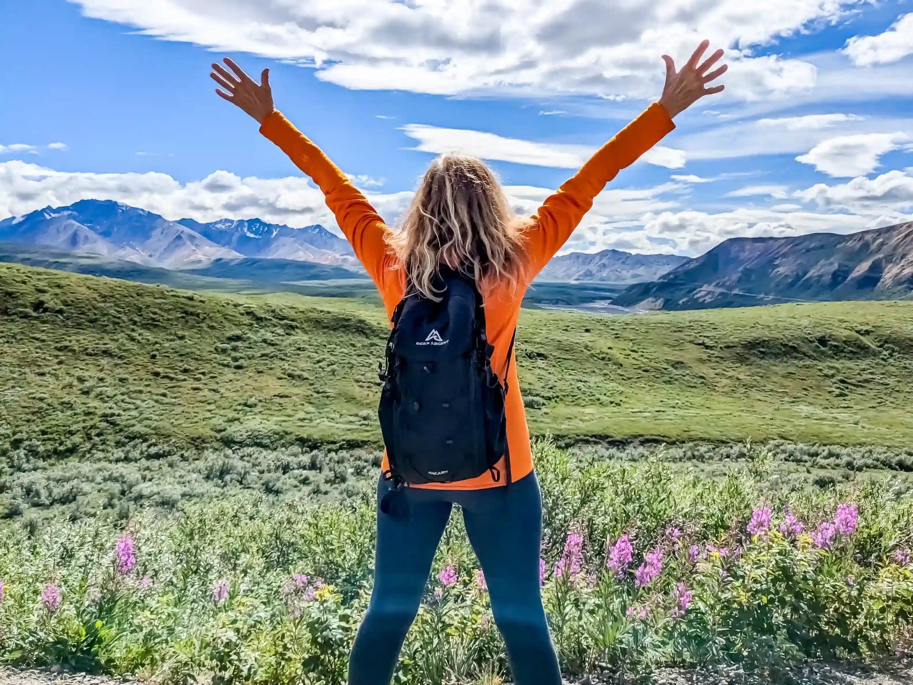 Hiker with arms outstretched overlooking Denali National Park in Alaska, wearing the Ancash Packable Daypack by Deep Ascent.