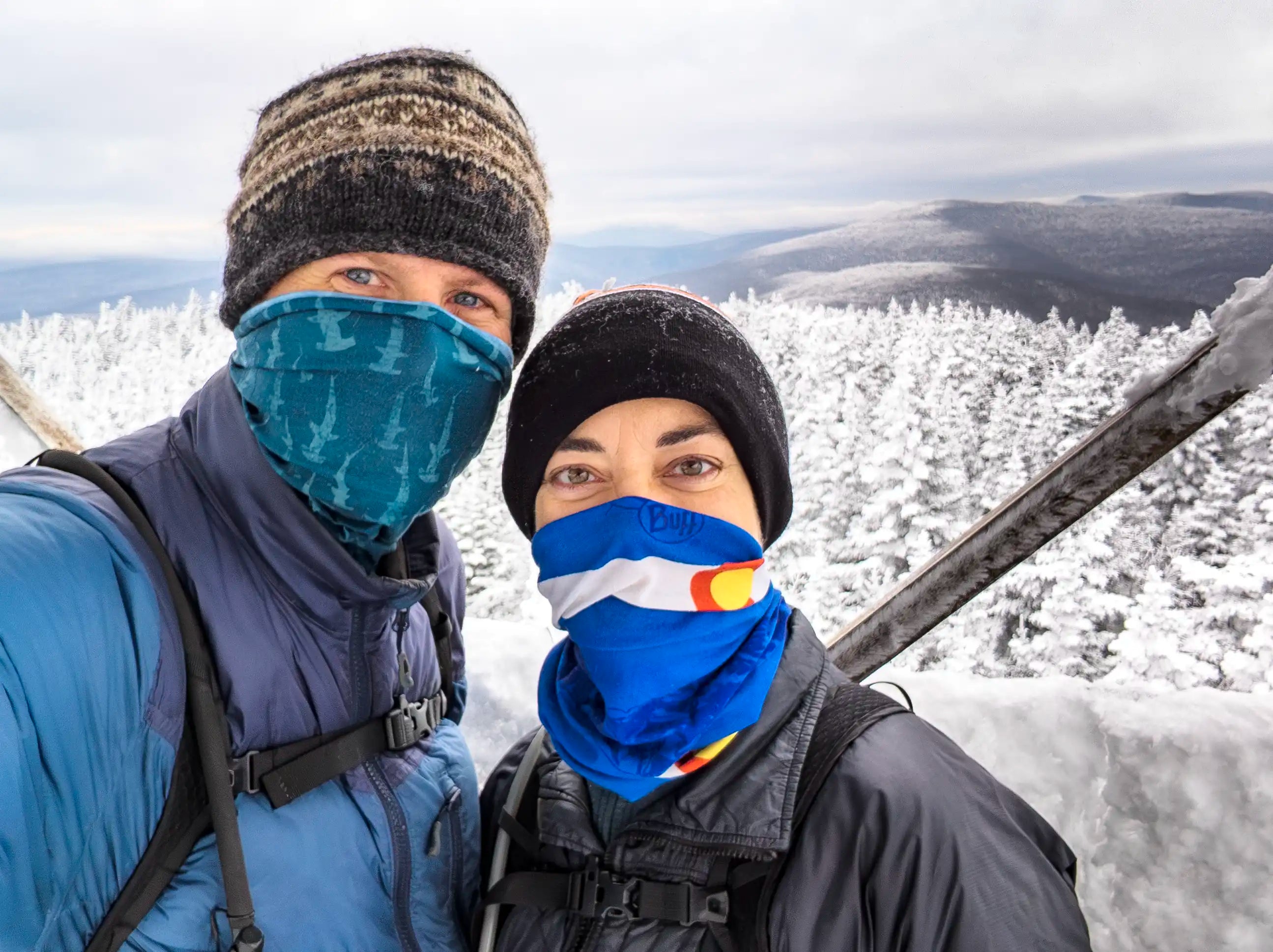 A man and woman standing on top of a fire tower on Balsam Lake Mountain in New York both both wearing the Ancash Packable Daypack by Deep Ascent.