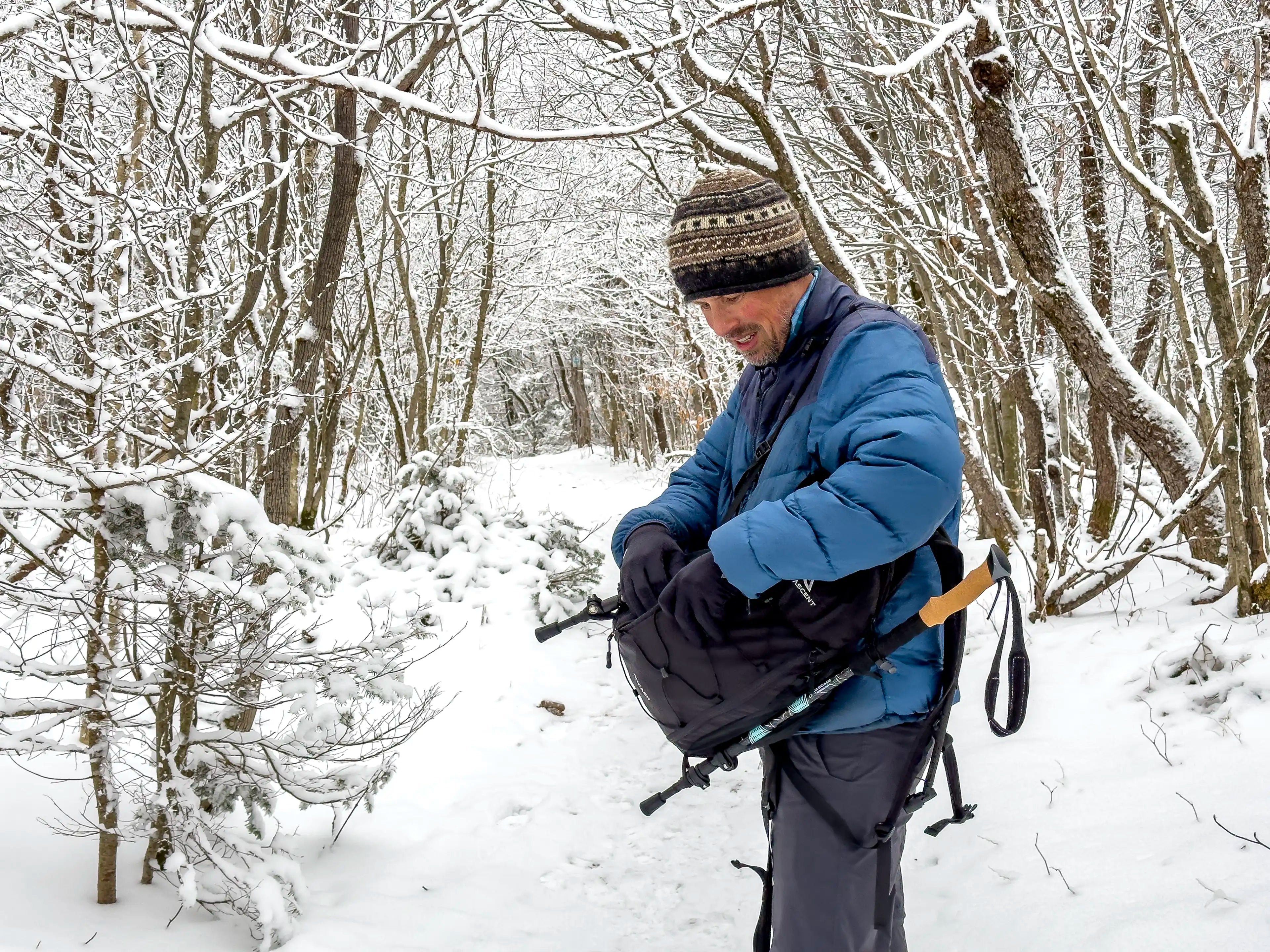 A male hiker reaching into his Ancash Packable Daypack by Deep Ascent.