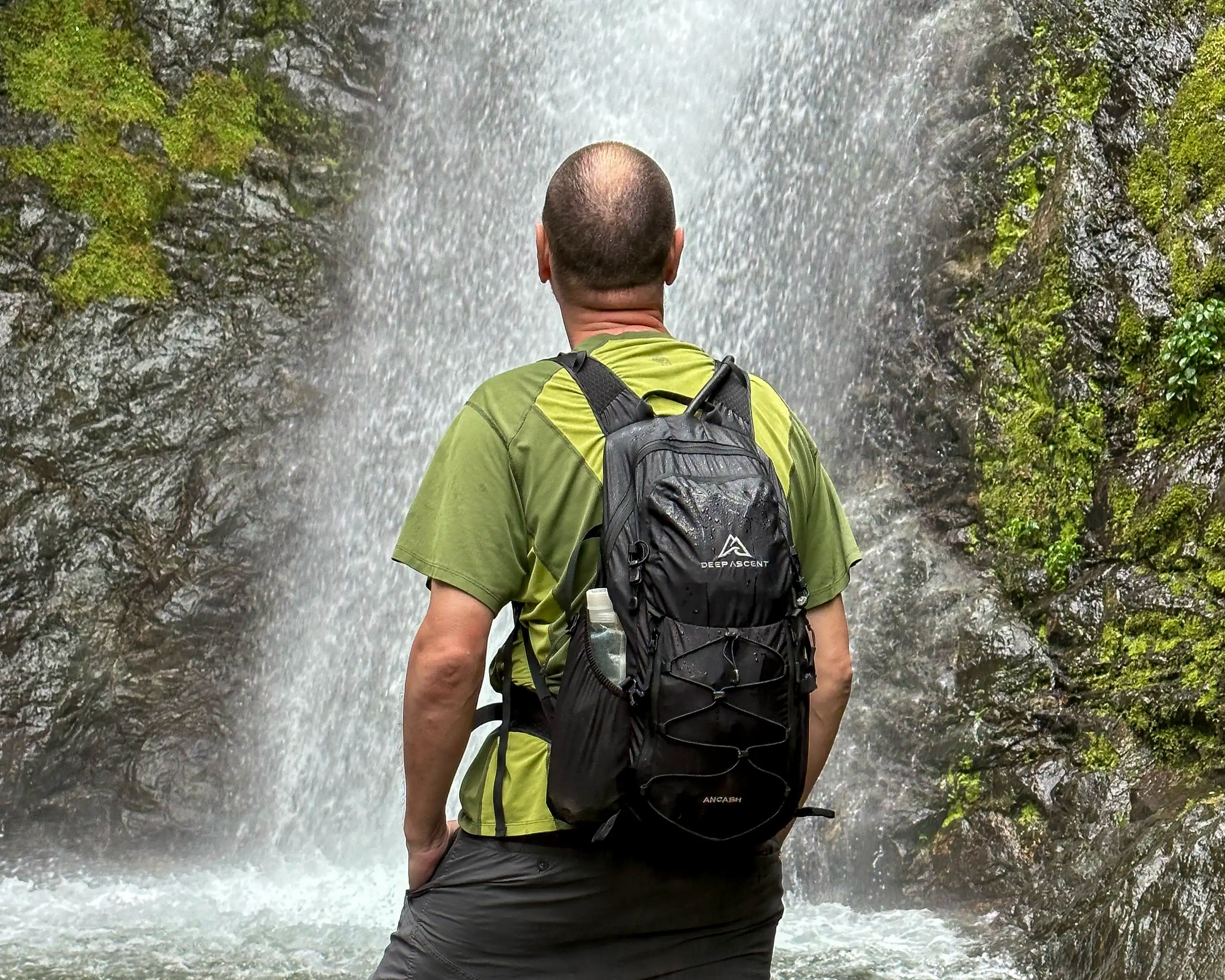 A man standing in front of a waterfall in Bucay, Ecuador wearing the Ancash Packable Daypack by Deep Ascent.