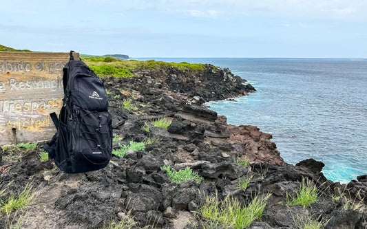 The Ancash Backpack Daypack hanging on a signpost on a cliff overlooking the ocean near La Loberia Beach in the Galapagos.