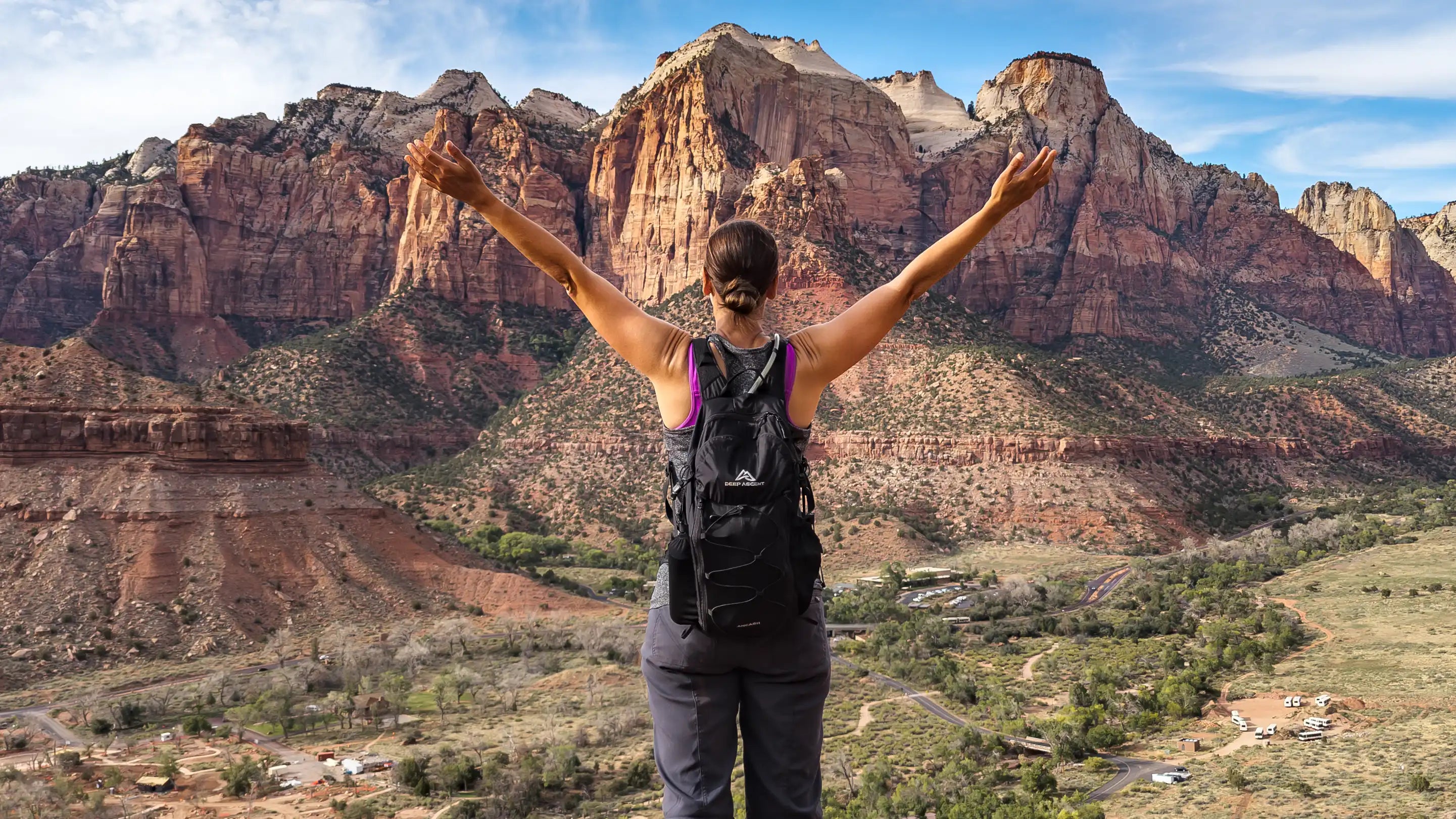 Hiker wearing the Ancash Packable Daypack overlooking Zion National Park from the top of Watchman Trail with arms outstretched.