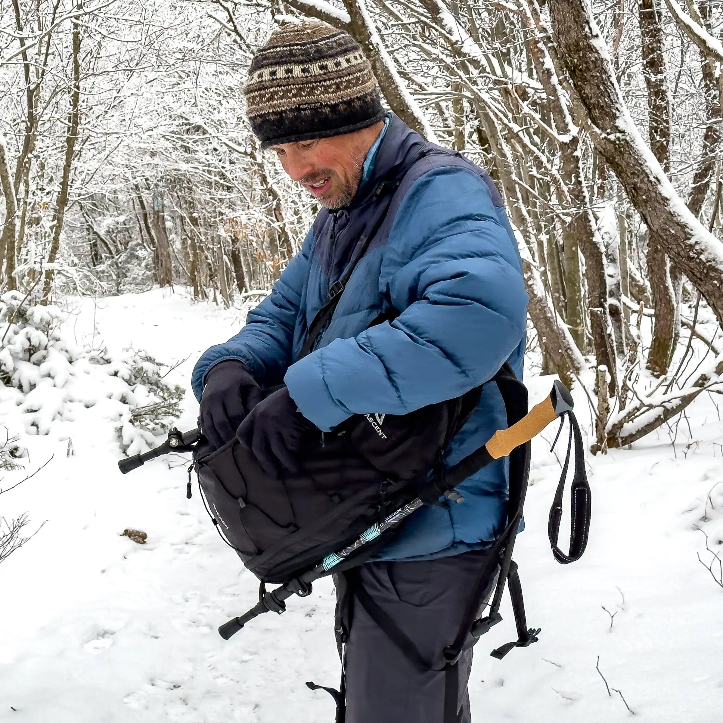 A hiker in the snow using the sling pocket of the Ancash Packable Daypack by Deep Ascent.