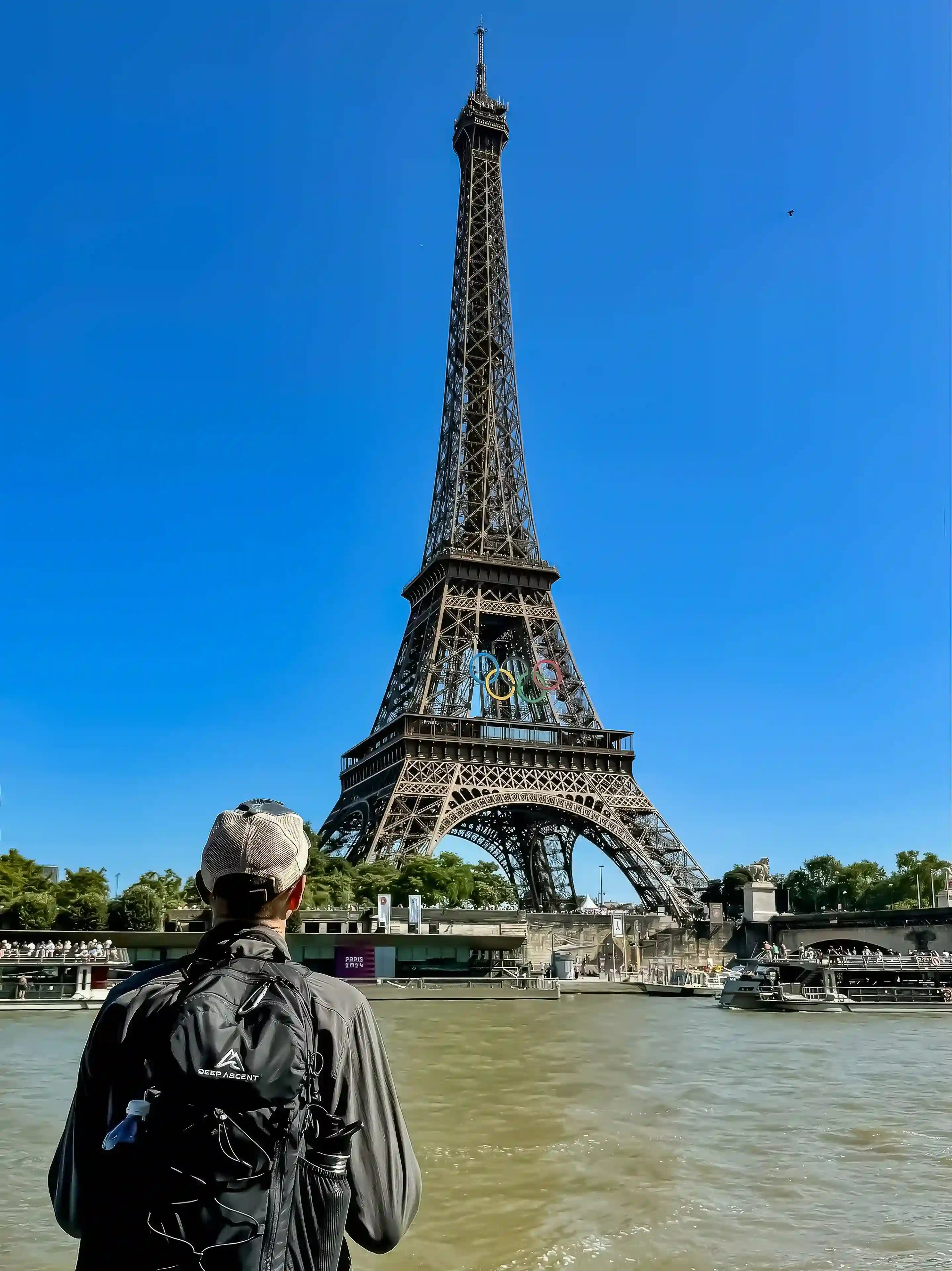 Man standing in front of the Eiffel Tower in Paris, wearing the Ancash Packable Daypack by Deep Ascent.