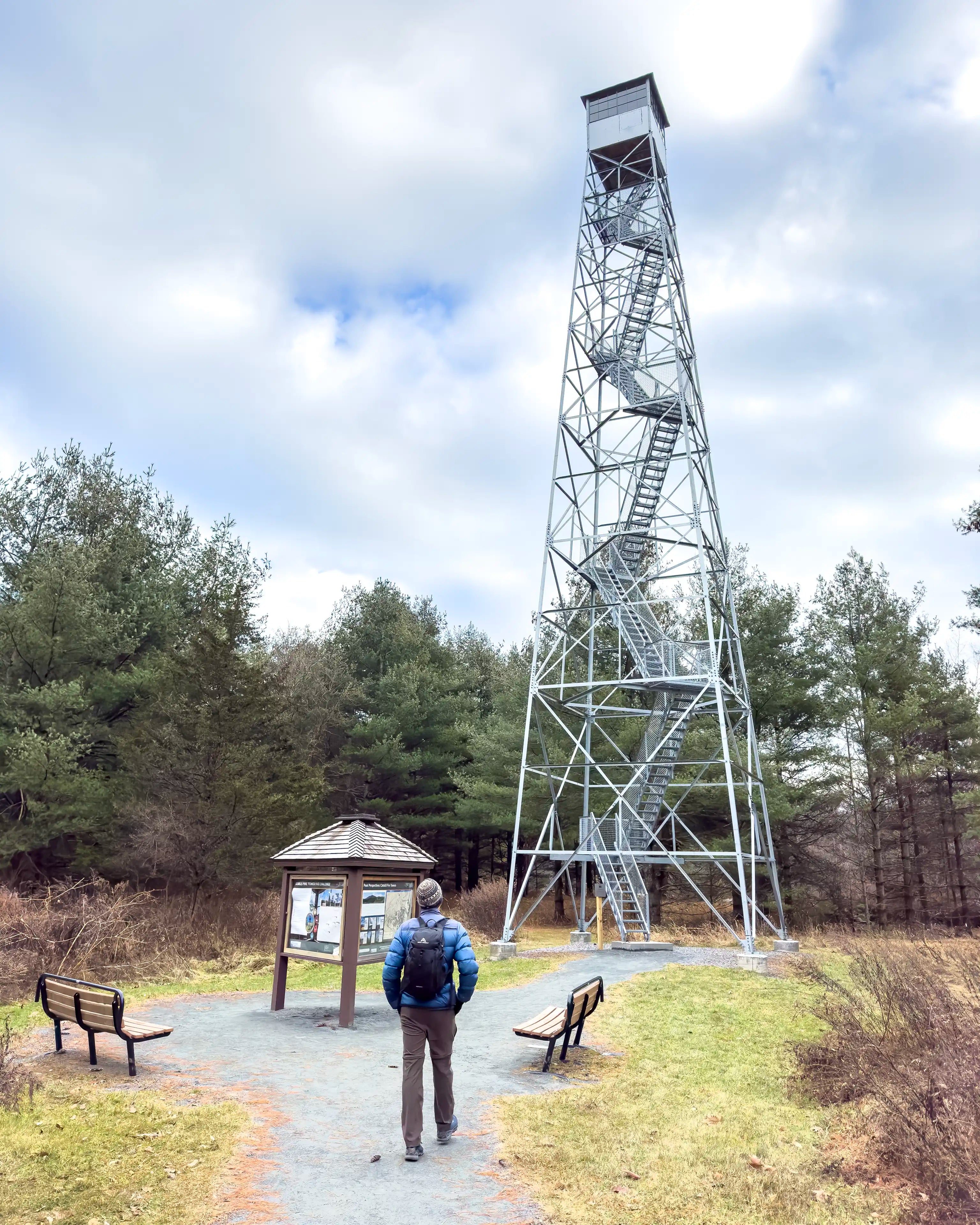 A man walking towards the Upper Esopus Fire Tower in Mt Tremper, New York wearing the Ancash Packable Daypack by Deep Ascent.