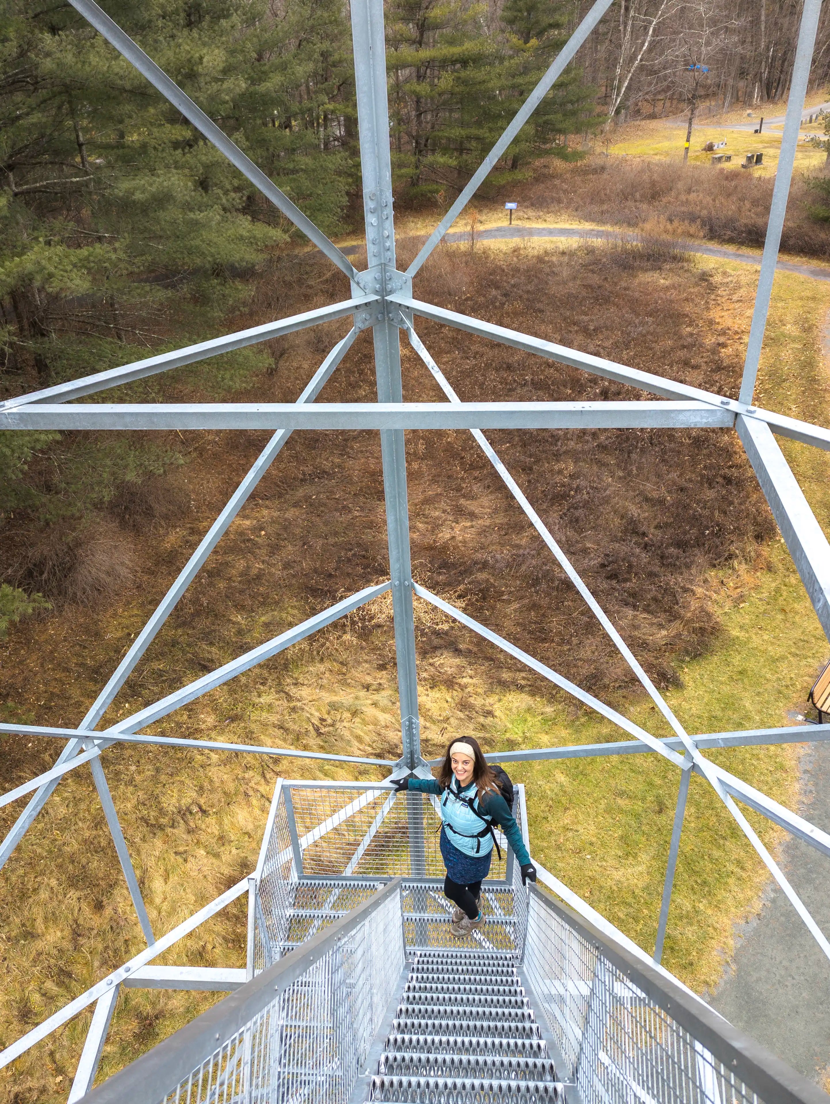 A woman standing on the Upper Esopus fire tower in New York wearing the Ancash Packable Daypack by Deep Ascent.