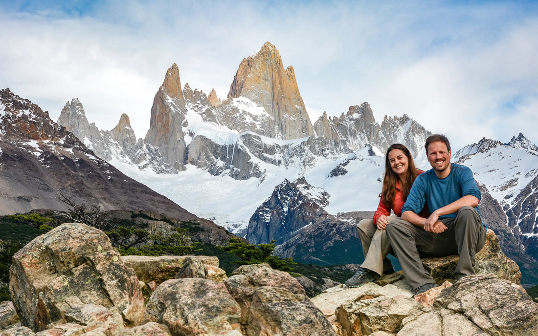 A man and a woman sitting on a rock in front of Monte Fitz Roy in Argentina's Patagonia.