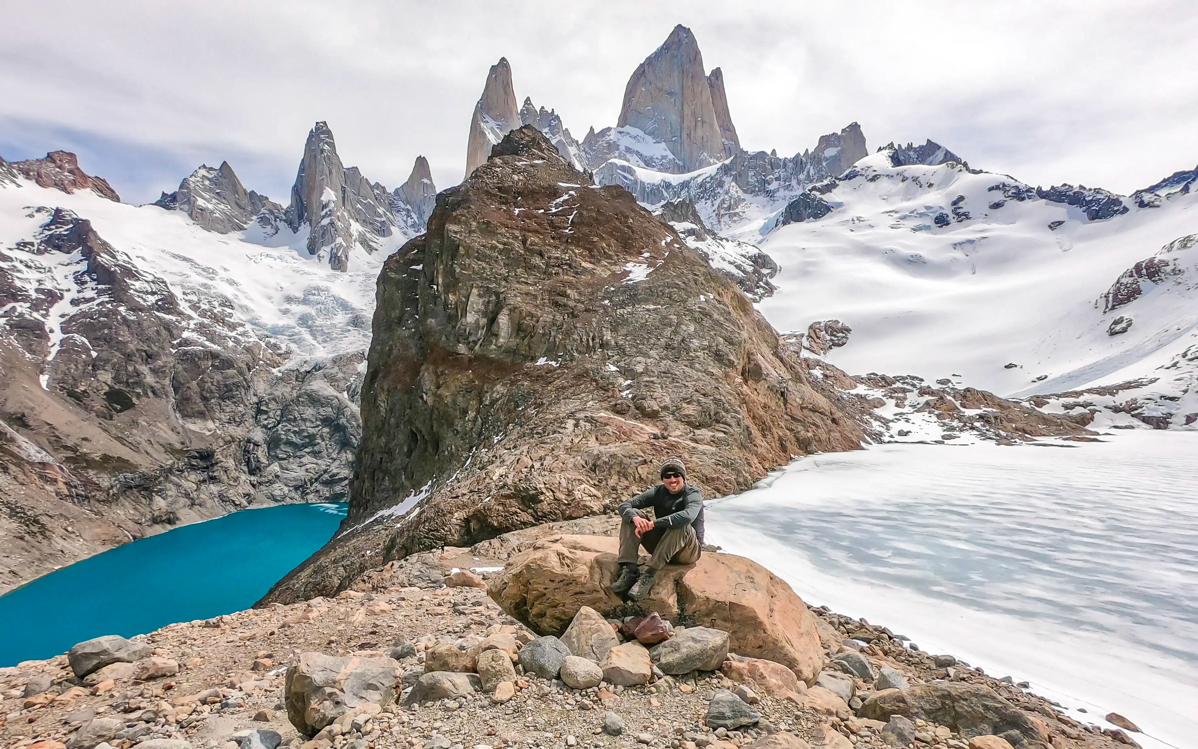 A man sitting on a rock in front of Fitz Roy in El Chaltén, Argentina.