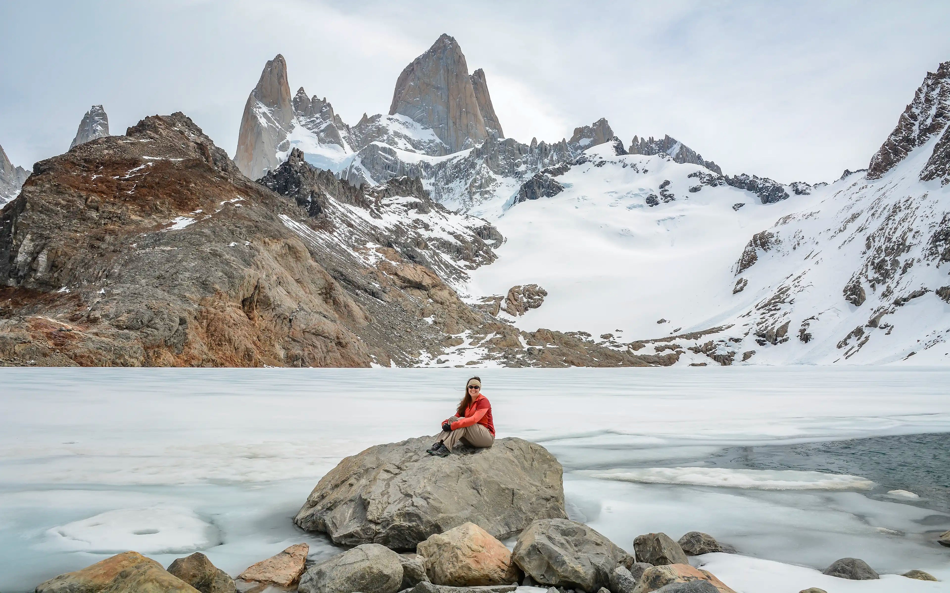 A woman sitting on a rock in front of Fitz Roy in El Chaltén, Argentina.