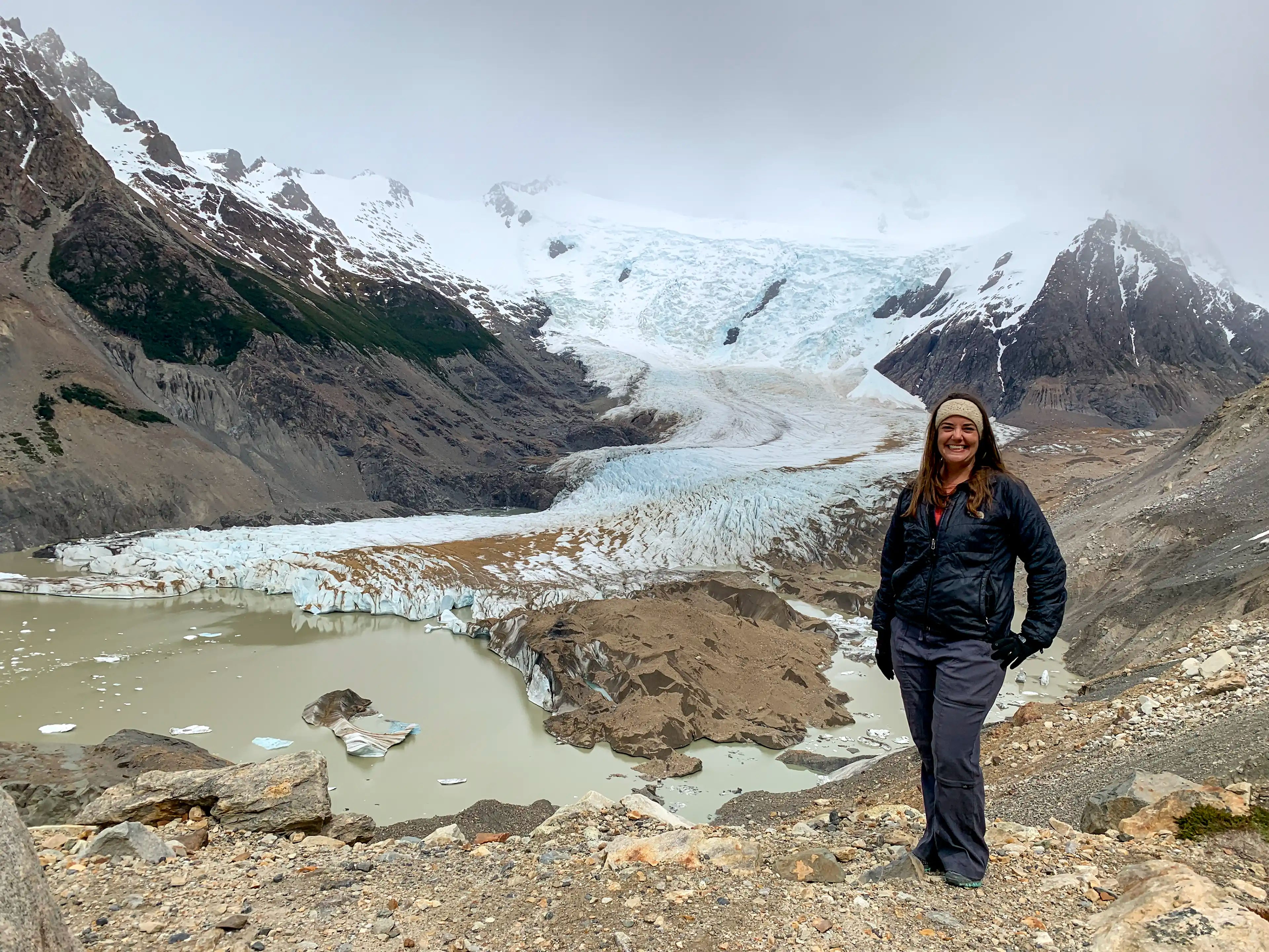 A woman standing in front of Laguna Torre in El Chaltén, Argentina.