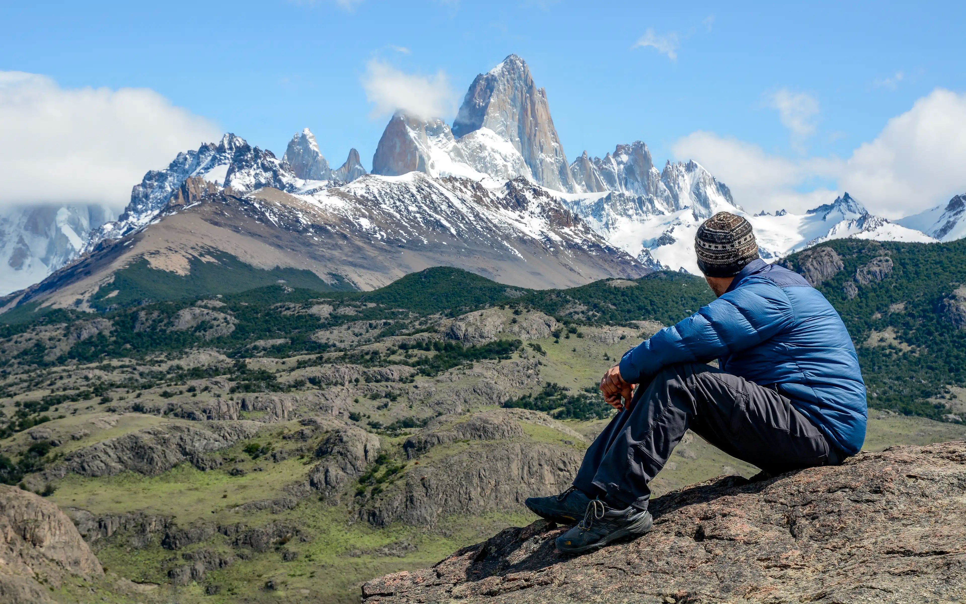 A man sitting on a rock at Mirador de los Cóndores in El Chaltén, Argentina overlooking Fitz Roy.