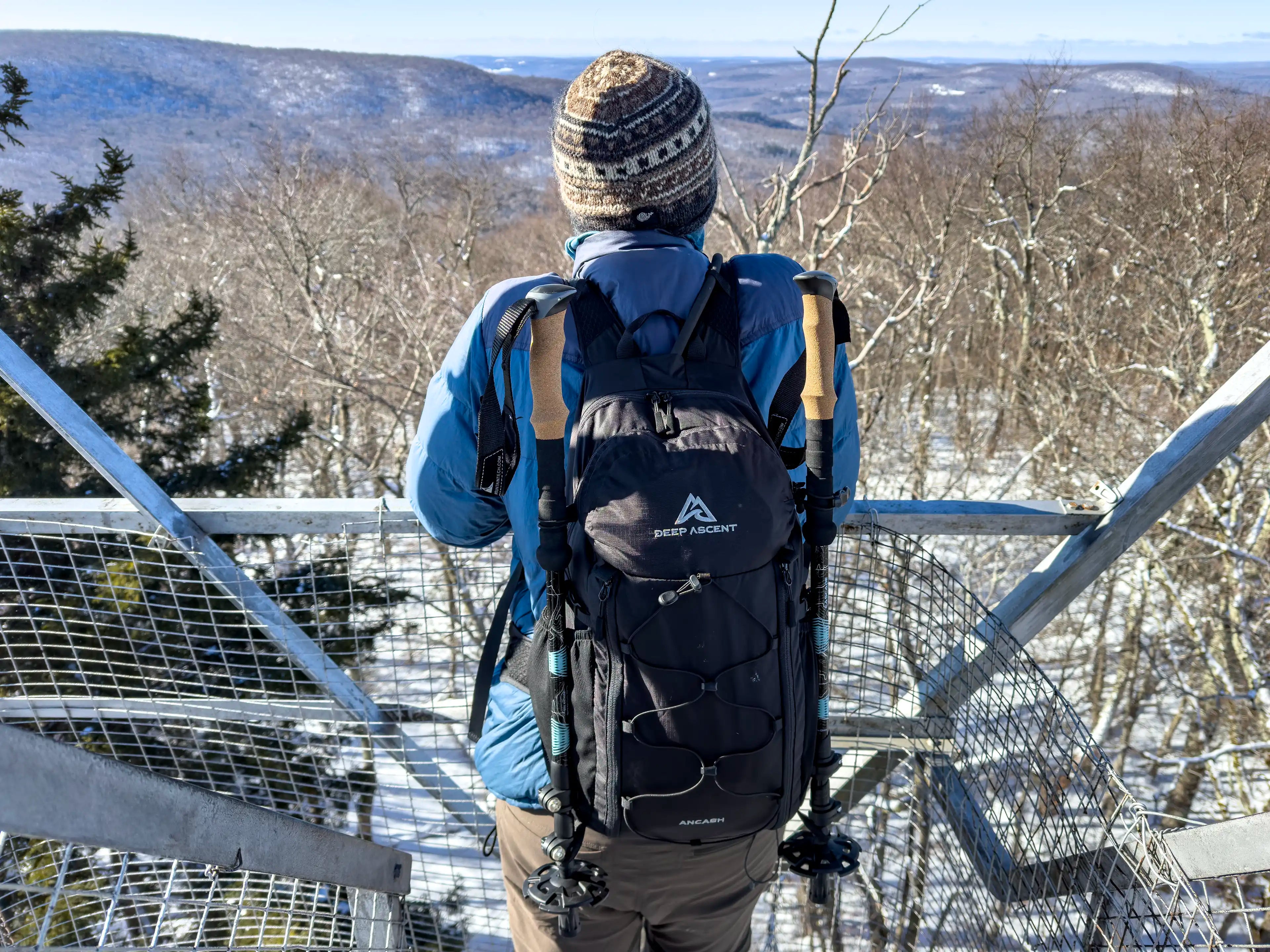 A male hiker standing on Red Hill Fire Tower in New York wearing the Ancash Packable Daypack by Deep Ascent.