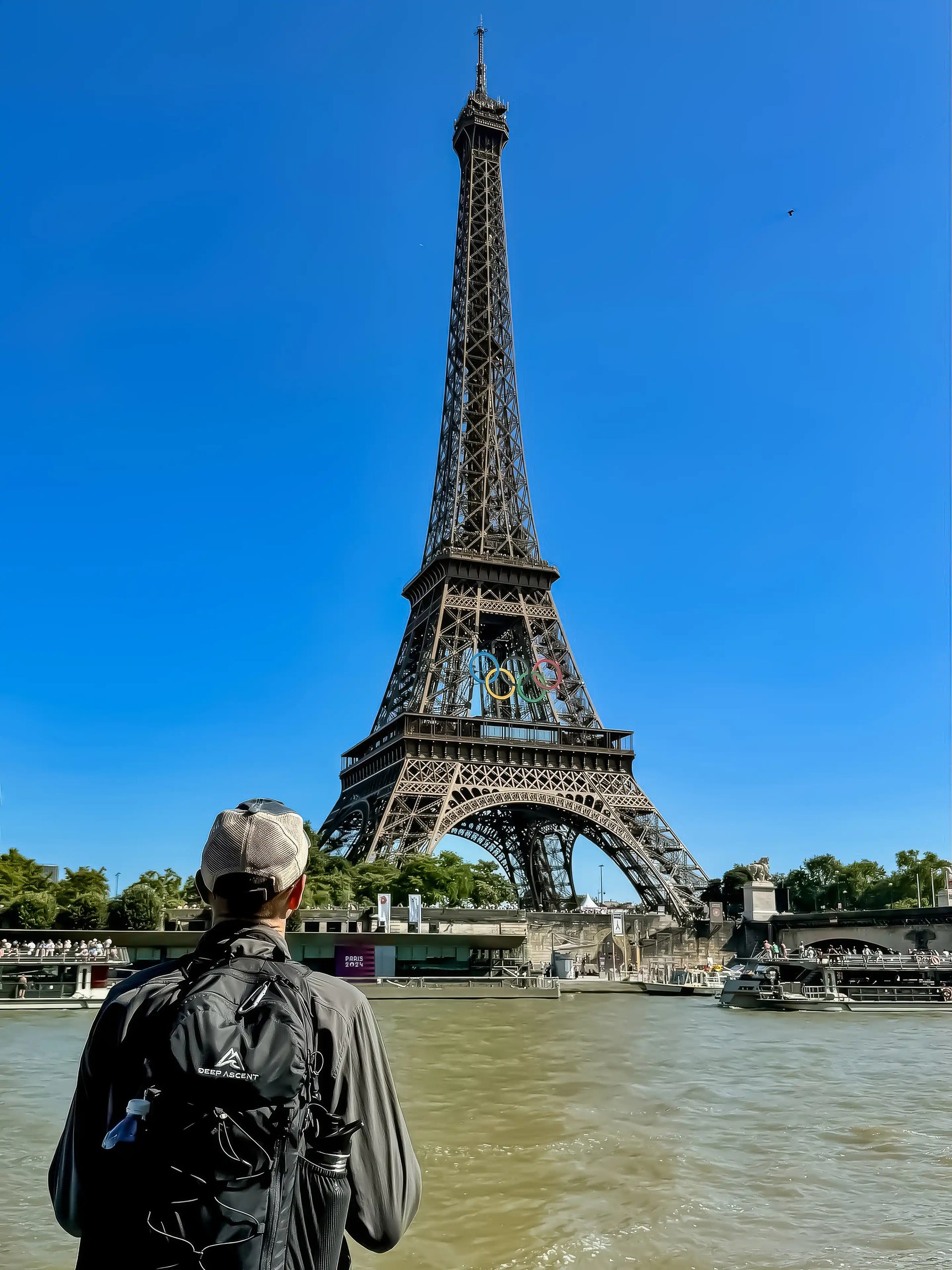 A man standing in front of the Eiffel Tower in Paris with the Ancash Packable Daypack by Deep Ascent.