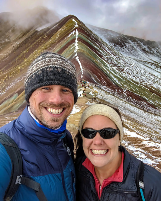 A man and woman standing in front of Rainbow Mountain outside of Cusco, Peru.