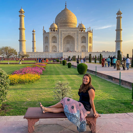 A woman sitting on a bench in front of the Taj Mahal in Agra, India.